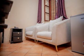 A room with a sofa, a small cabinet, and a refrigerator.