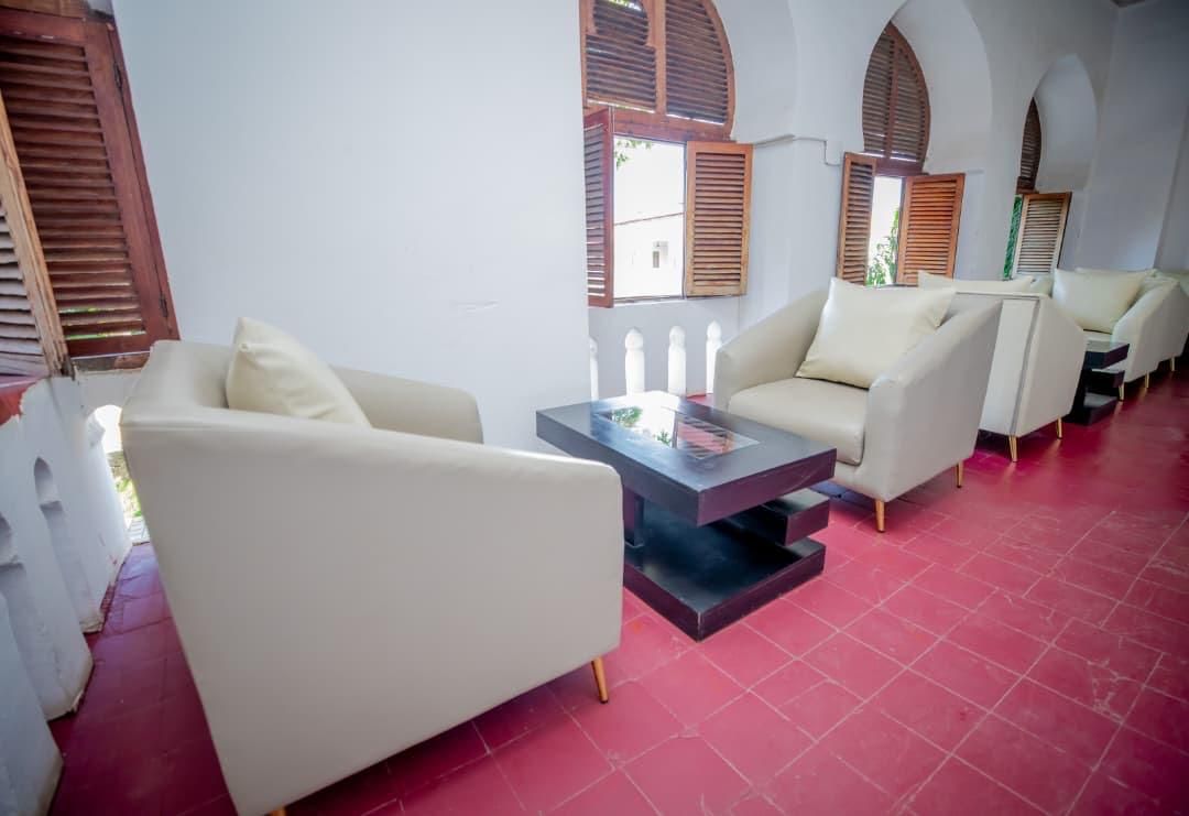 A seating area with white sofas and a central coffee table, featuring a white railing and wooden shutters on the windows.