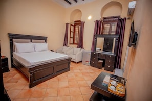 Habitación de hotel con cama, sofá, escritorio y bandeja con productos para el desayuno, además de un armario.
