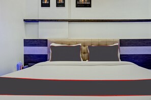 Una cama con cabecera, almohadas y una colcha.
