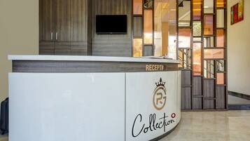 A reception desk with a 'RECEPTION' sign, a logo with a crown and 'R' inside a circle, and the word 'Collection' below.