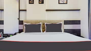 Habitación de hotel con una cama grande, dos almohadas, una mesita de noche con una botella de agua y una obra de arte enmarcada en la pared.