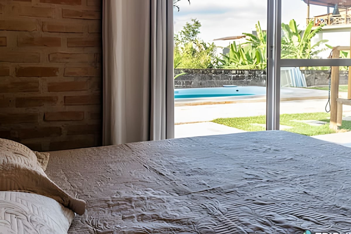 A room with a large window overlooking a swimming pool and greenery.