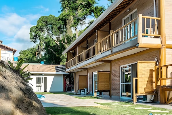 A two-story building with a balcony, large windows, and a covered outdoor area. - Recanto da Feiticeira (Ilhabela)