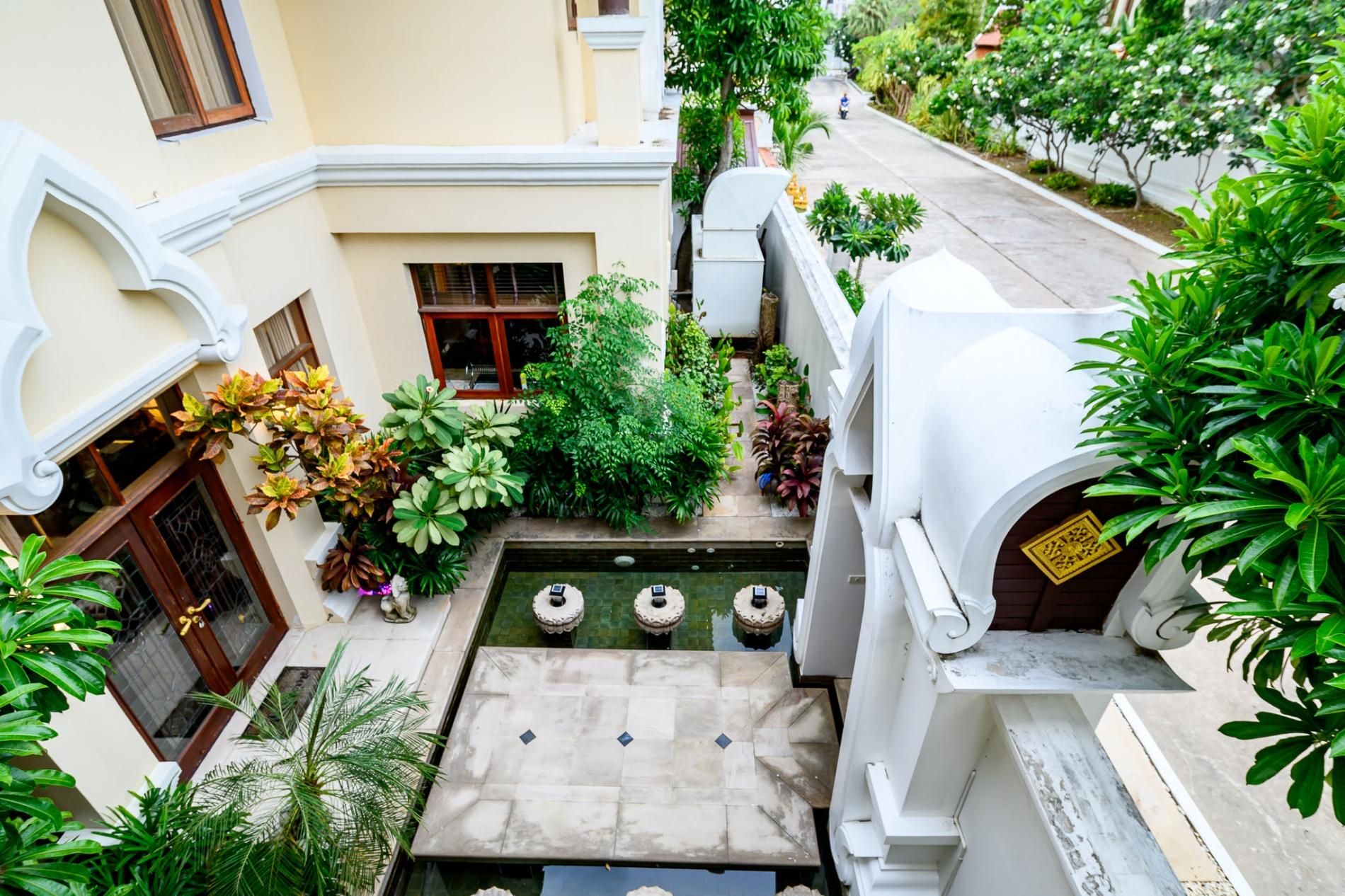 A courtyard with a small pool, surrounded by lush greenery and traditional architecture.