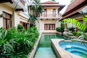 Un pati amb piscina, envoltat de vegetació exuberant i arquitectura tradicional.