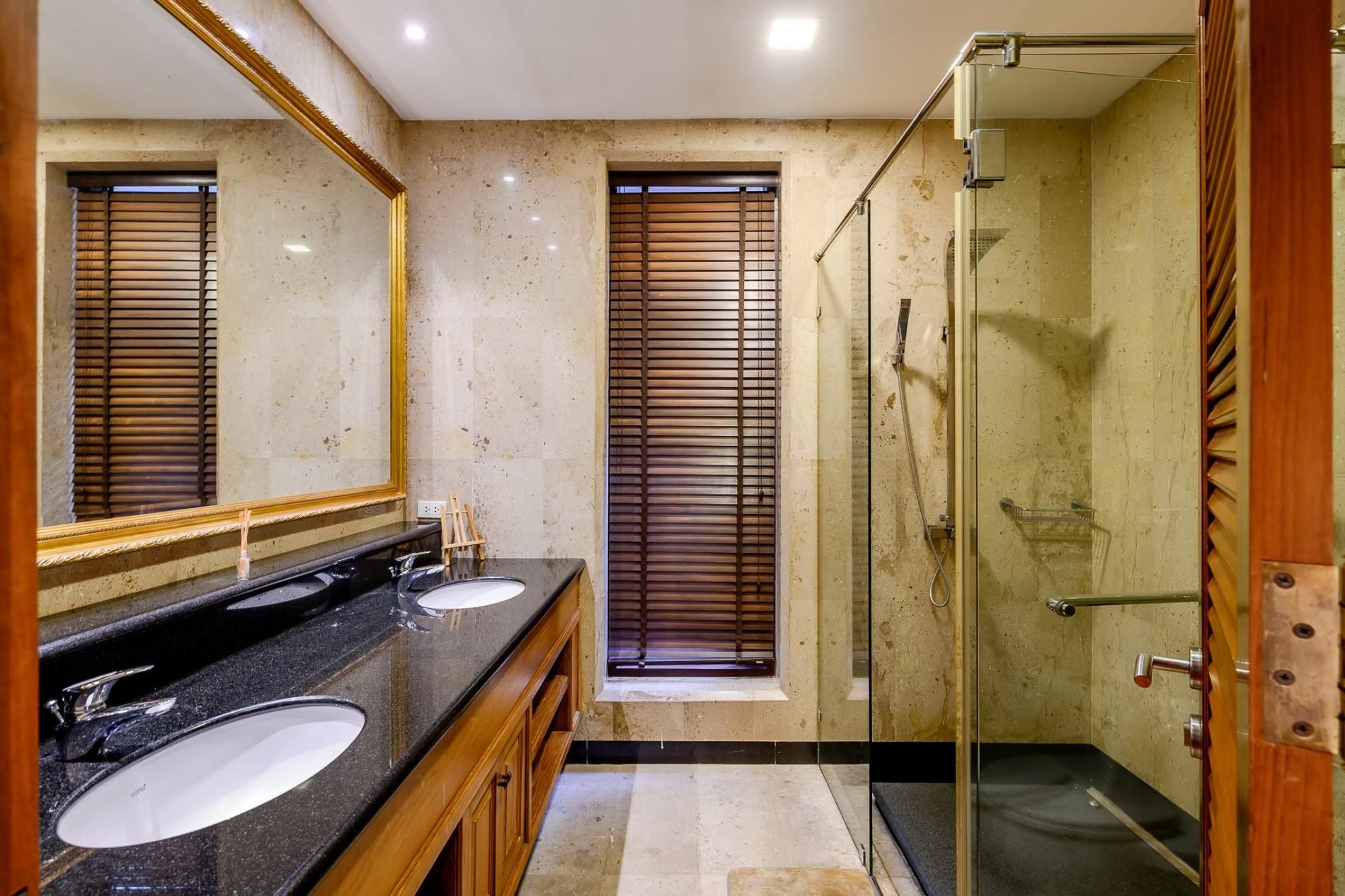 A bathroom with two sinks, a mirror, and a shower.