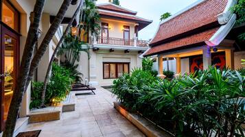 A courtyard with a pool, surrounded by lush greenery and traditional architecture.
