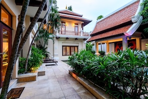 Un patio con piscina, rodeado de vegetación exuberante y arquitectura tradicional.