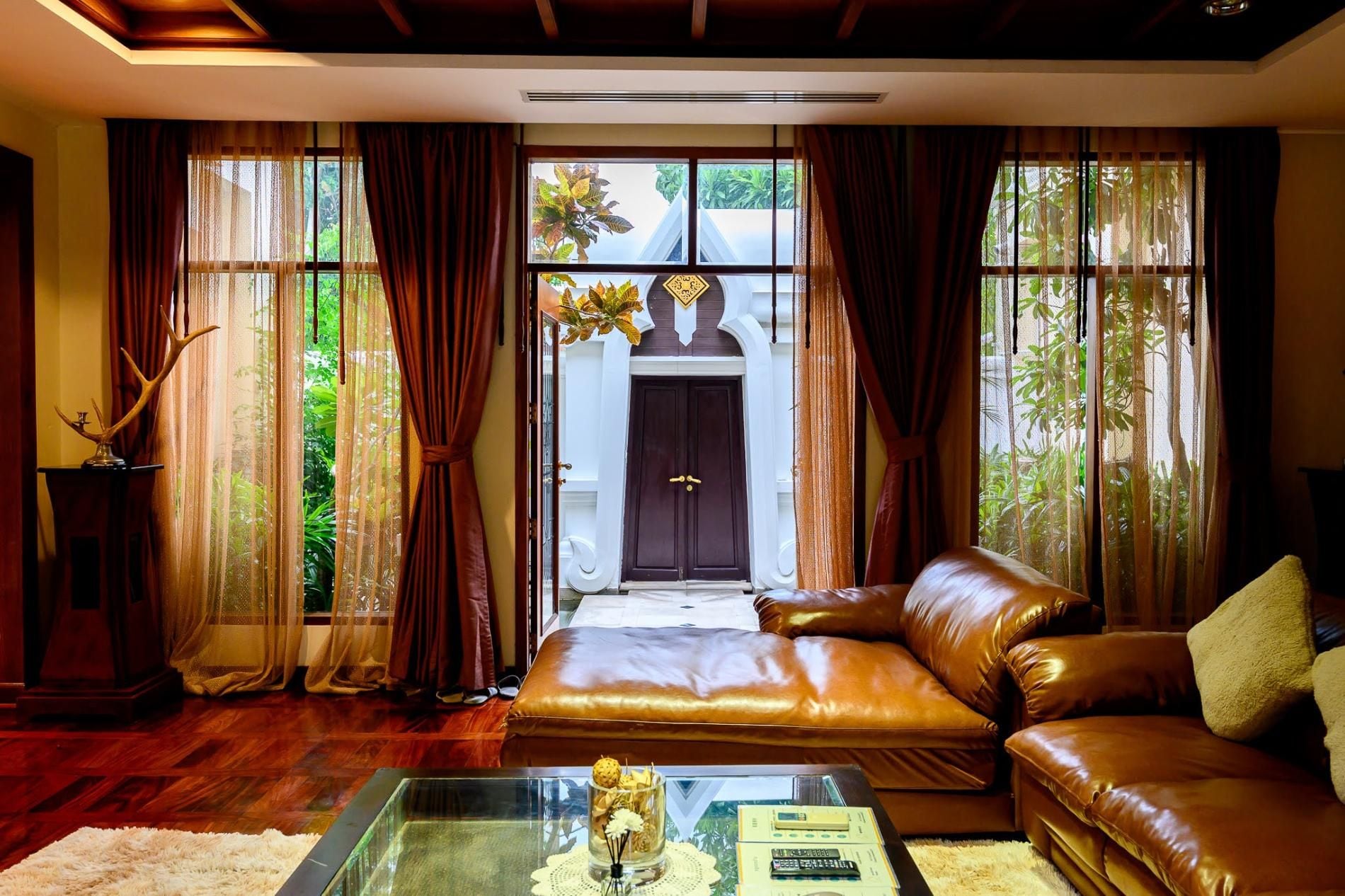 A living room with a leather sofa, a glass coffee table, and a view of a traditional building through large windows.