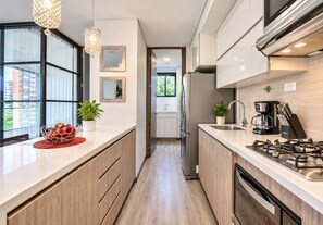 A modern kitchen with a gas stove, coffee maker, and a sink. - 2-bedroom apartment in beautiful Medellín with cool AC and infinity pool (Medellín)