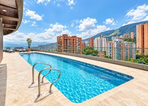 A rooftop swimming pool with a clear view of surrounding high-rise buildings and a distant cityscape. - 2-bedroom apartment in beautiful Medellín with cool AC and infinity pool (Medellín)