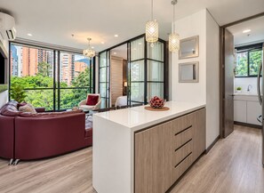 Ein modernes Interieur mit einer gebogenen Couch, einem Essbereich und einer Küche mit großem Fenster.