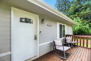 A white door with a window, a porch with two rocking chairs, and a 'Be Kind' sign. - Modern Lakeside Escape w/ Sauna + Mountain Access (Snohomish)