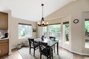 A dining area with a table, chairs, a chandelier, and large windows. - Modern Lakeside Escape w/ Sauna + Mountain Access (Snohomish)
