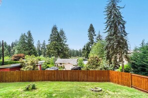 A residential backyard with a wooden fence, a lawn, and a house in the background. - Modern Lakeside Escape w/ Sauna + Mountain Access (Snohomish)
