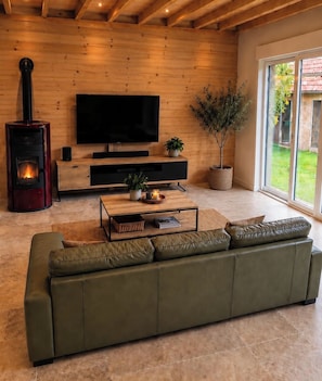 A modern living room with a sofa, a TV, a fireplace, and a large window. - The Cocoon of Ourville (Ourville-en-Caux)