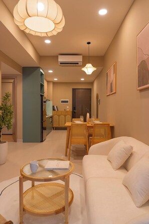 A modern living room with a sofa, dining table, and chairs, a kitchen area, and a hallway leading to a bedroom. - Urban 2BR + 1BA | Central D1 | 500m Bui Vien (Thành phố Hồ Chí Minh)