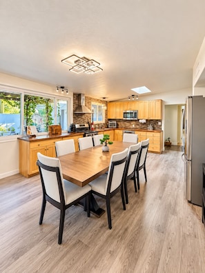 Une cuisine moderne dotée d’un îlot central, de meubles en bois et d’un coin repas avec une table et des chaises.
