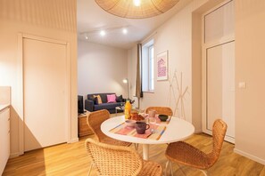 A modern living room with a round dining table, wicker chairs, a sofa, and a window with a view. - Charming Apartment 1br/2p - Lyon (Lyon)