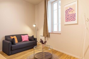 A modern living room with a grey sofa, a glass coffee table, and a window with curtains. - Charming Apartment 1br/2p - Lyon (Lyon)
