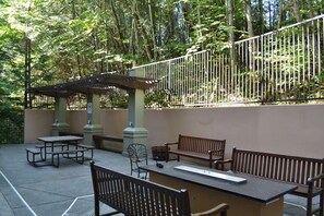 Ein Außenbereich mit einer Terrasse, Picknicktischen, Bänken und einer Pergola.