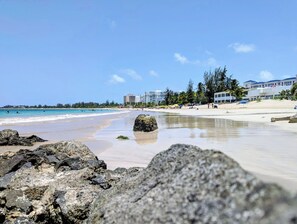 A beach with clear skies, a sandy shore, and large rocks in the foreground. - Seaside 3E - Luxury 2Br Apt on the Beach - Ocean View - Steps to Paradise (Carolina)
