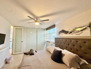 A bedroom with a bed, a ceiling fan, a sliding door, and a window. - Seaside 3E - Luxury 2Br Apt on the Beach - Ocean View - Steps to Paradise (Carolina)