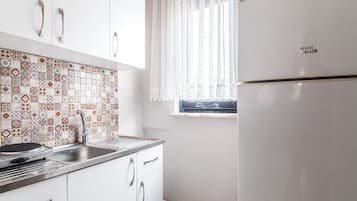 A kitchen with white cabinets, a stainless steel sink, and a tiled backsplash.