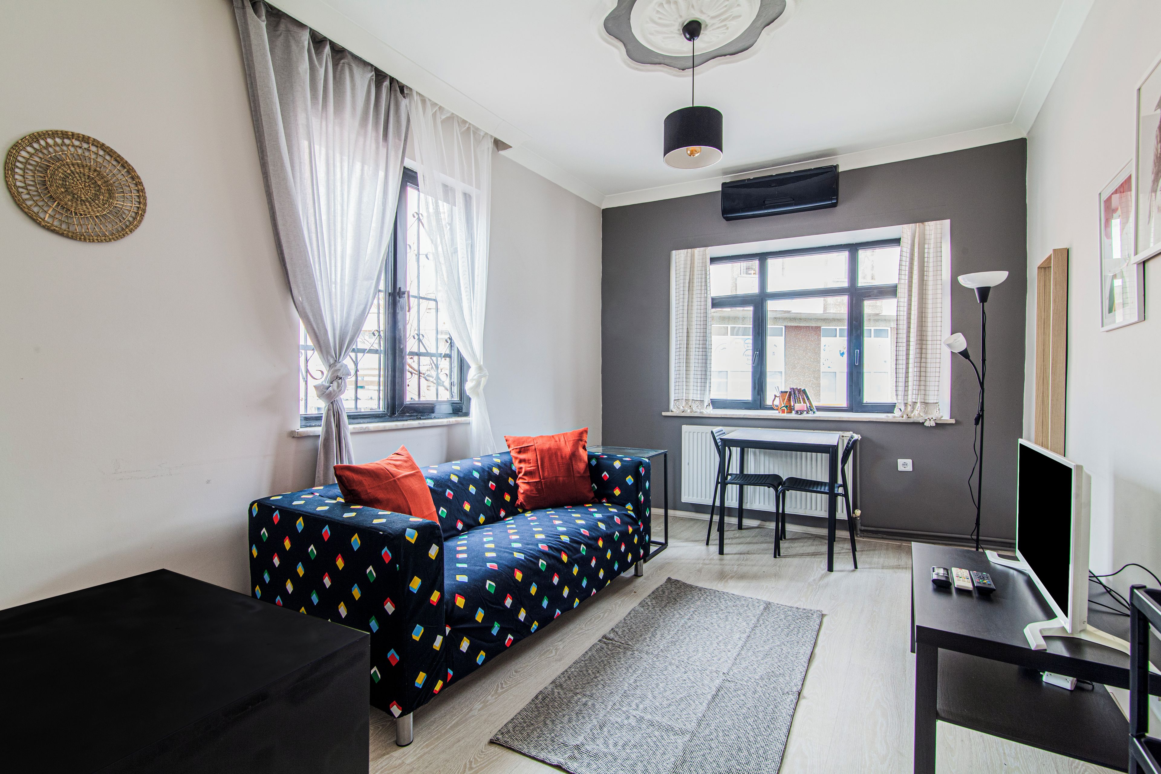 Una sala moderna con un sofá, una mesa de comedor y un mueble negro para televisor.