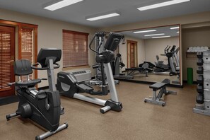 Ein Fitnessraum mit Cardiogeräten, Gewichtsbänken und einer Spiegelwand.