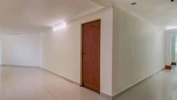 A spacious, empty hallway with white walls and a wooden door.