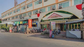 A multi-story building with a prominent OYO Kamini sign, several storefronts, and parked motorcycles.