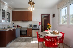 Una cocina moderna con armarios marrones, una mesa de comedor con sillas rojas y una lámpara colgante.