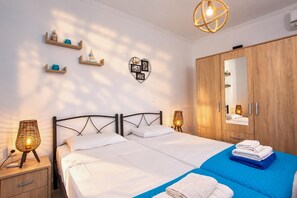 A double bed with white linens, a wooden wardrobe, a mirror, and wall-mounted shelves with decorative items. - Villa Kalimera - Three Bedroom Villa, Sleeps 6 (Gennadi)