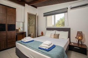 Un dormitorio con cama, armario, espejo, aire acondicionado y lámpara de noche.