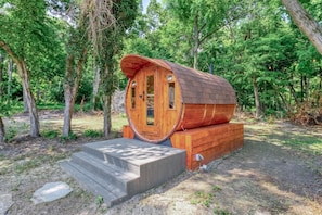 Una cabaña de madera con techo curvo, una puerta principal y un pequeño porche con escalones de acceso.