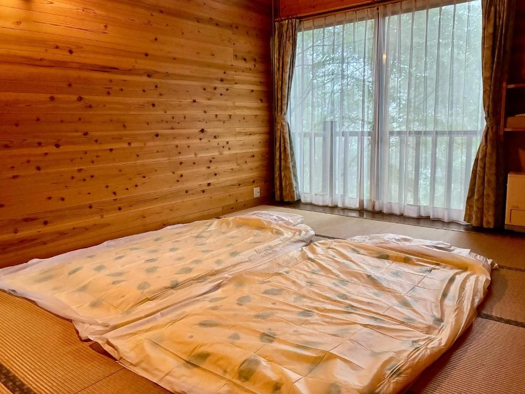 Una habitación con una cama grande, paredes de madera y vistas a través de una ventana.