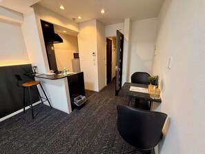 Une chambre d’hôtel compacte comprenant un coin cuisine, un espace repas et un petit coin salon.