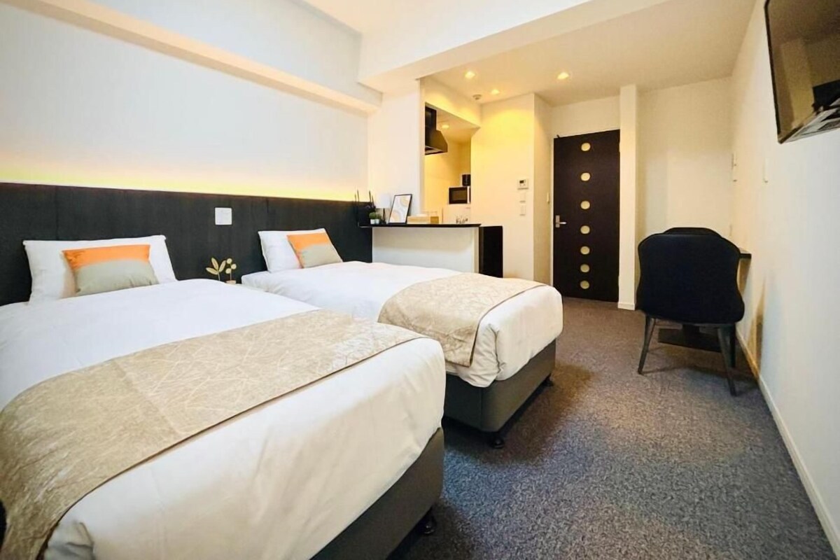 Une chambre d’hôtel avec deux lits, un bureau et une chaise.