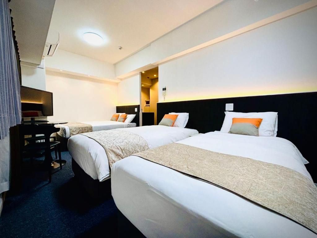 A hotel room with two beds, a desk, and a television.