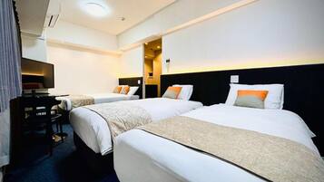 A hotel room with two beds, a desk, and a television.
