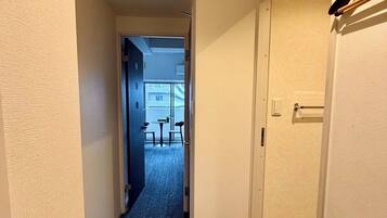 A narrow hallway with carpeted flooring leading to a room with a door.