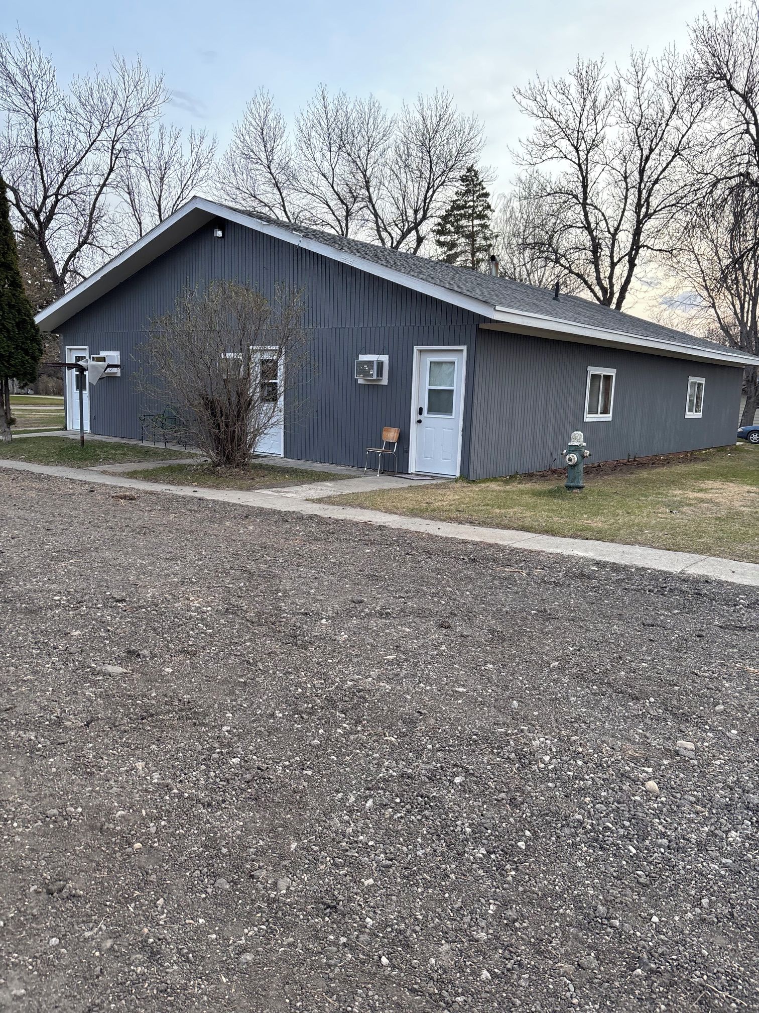 A single-story building with a grey exterior, a white door, and a small porch area.