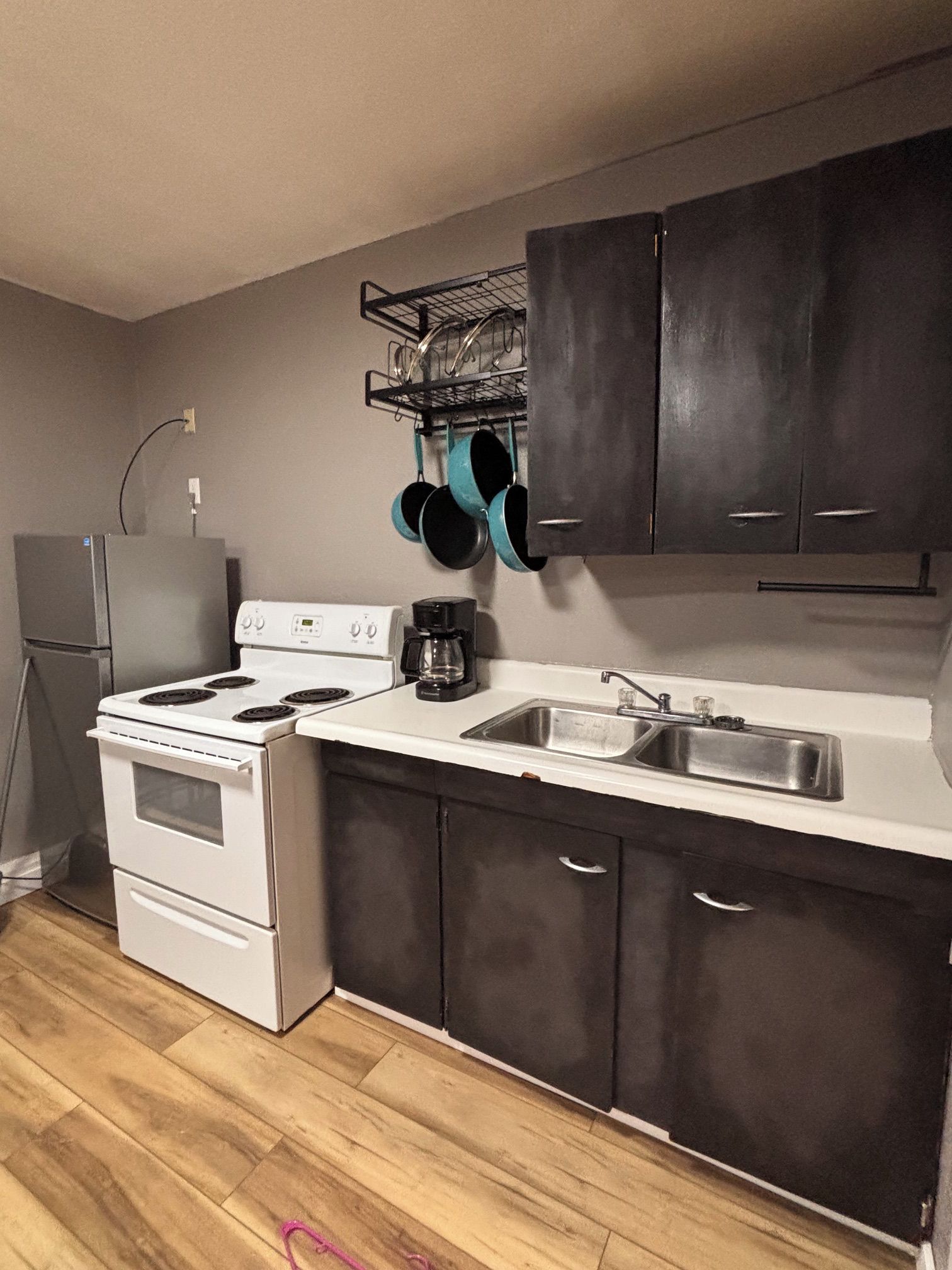 A kitchen with a stove, oven, sink, and dark cabinets.