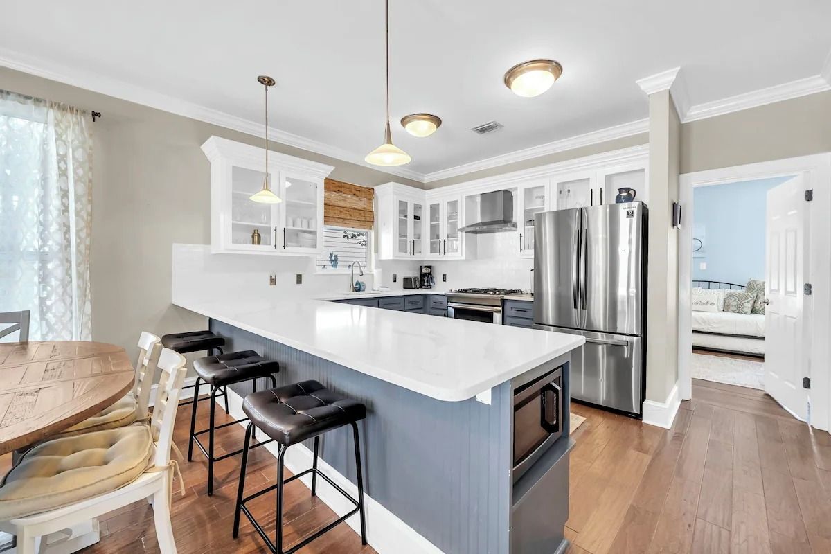 A modern kitchen with a central island, stainless steel appliances, and bar stools.