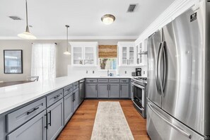 A modern kitchen with grey cabinets, a stainless steel refrigerator, and a white countertop. - 🚲Sugar Sand Bungalow | Pet Friendly | Bikes | Spacious Balcony | Walk to Beach🐾 (Santa Rosa Beach)