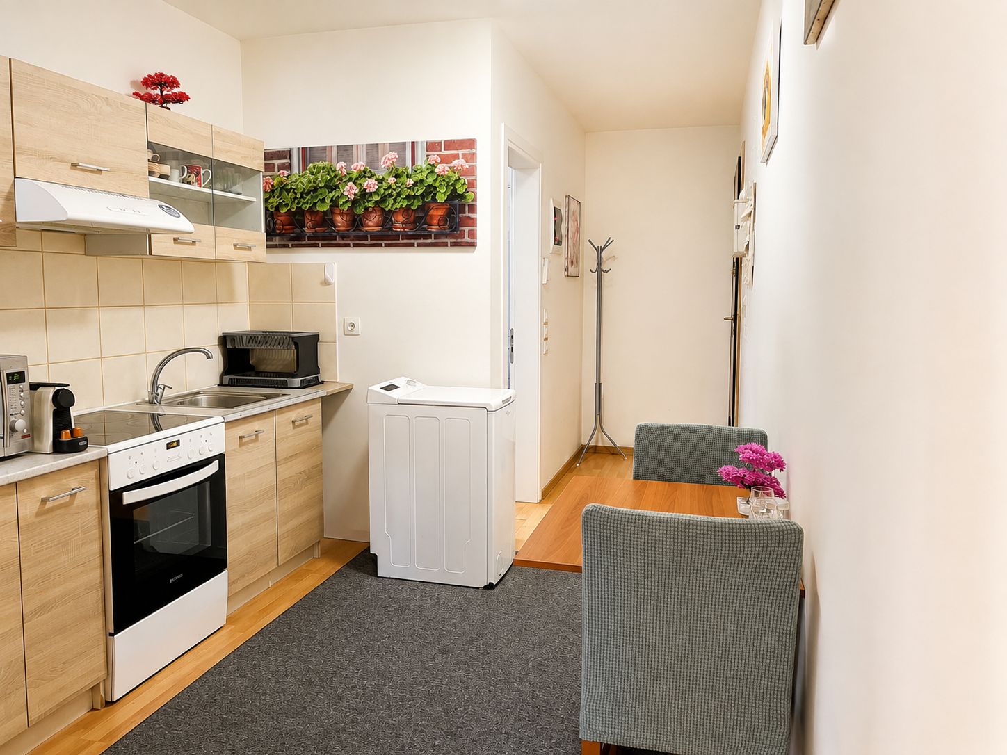 A compact kitchen with a microwave, oven, and a small dining area with a chair and table.