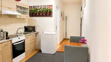 A compact kitchen with a microwave, oven, and a small dining area with a chair and table.