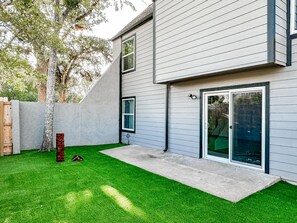A modern two-story house with a flat roof, a concrete patio, and a well-maintained lawn. - Gamer's Day Den - Walk to Kyle Field (College Station)
